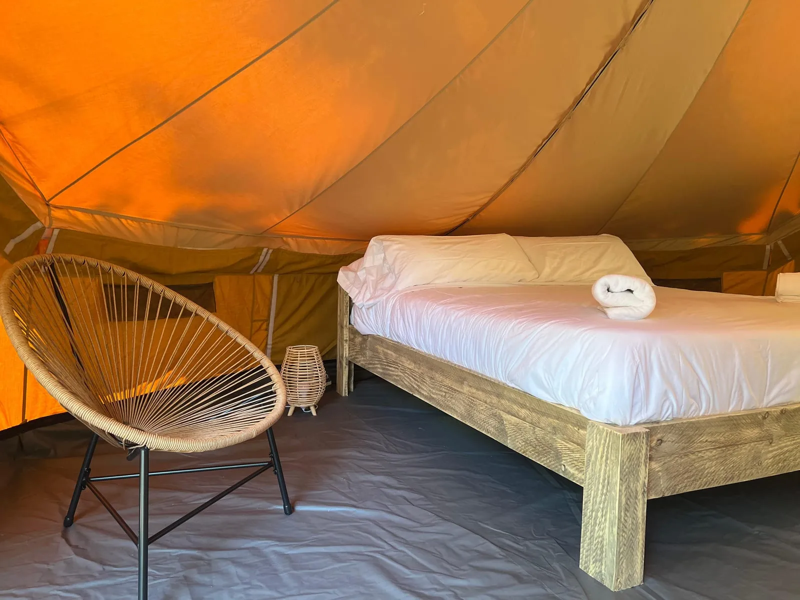 Interior de la tenda Bruc amb llit de matrimoni i cadira penjant