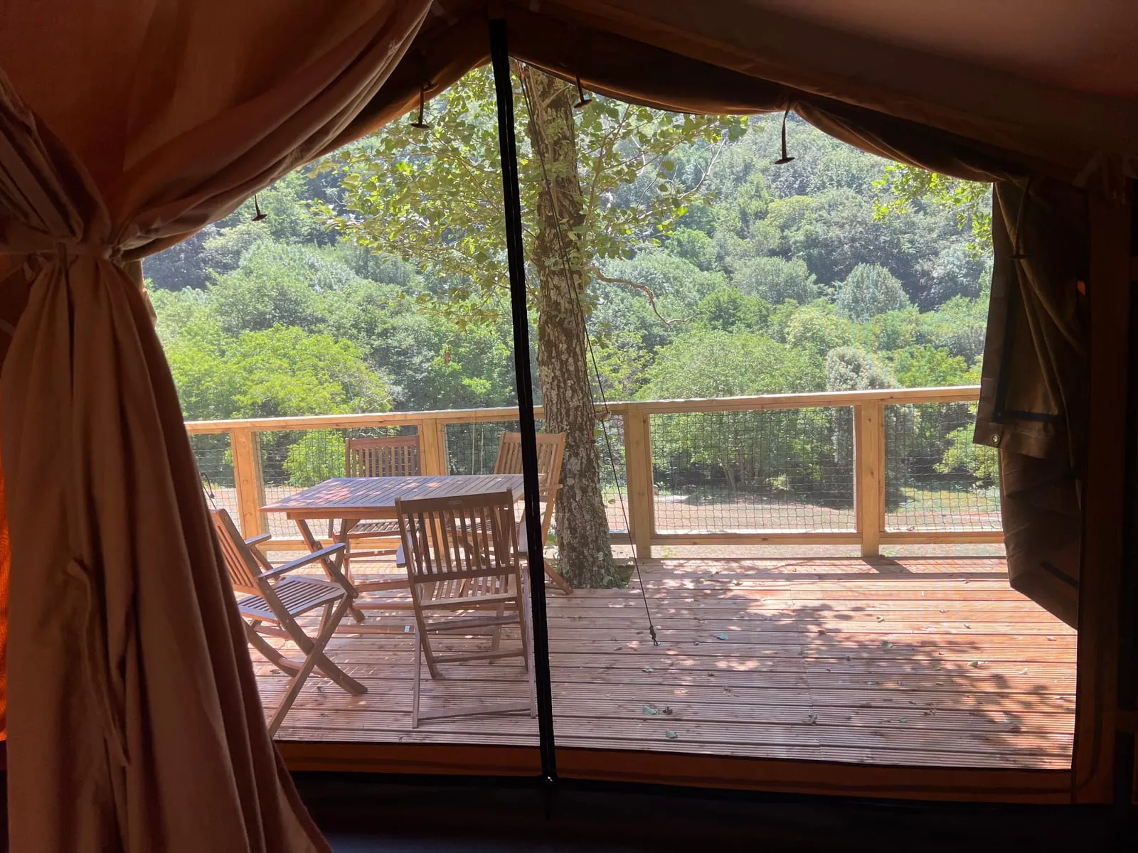 Vista des de la tenda Bruc cap a la terrassa amb taula i el bosc del Montseny