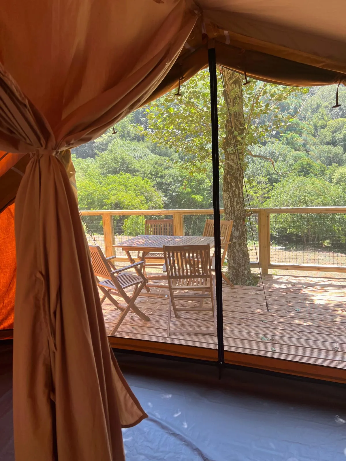 Interior de la tenda Bruc obert a la terrassa de fusta i el bosc