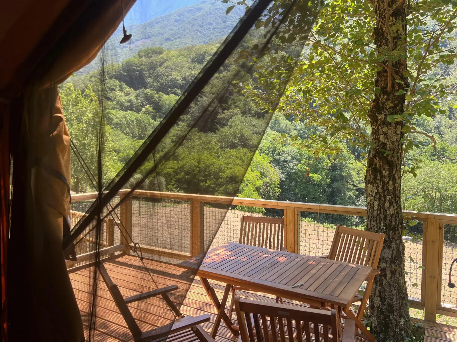 Terrassa de la tenda Bruc amb taula i cadires entre grans arbres