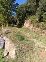 Pista de terra al costat d’un mur de pedra, just en sortir del càmping