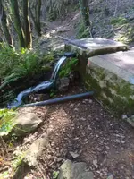 Agua que cae de un tubo junto a un depósito
