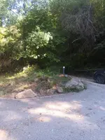 Camí asfaltat al costat de l’entrada, amb roques i una barrera